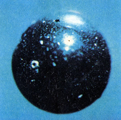 Стеклянный шарик (диаметр около 1 мм) из лунной пыли (под микроскопом); виден след удара микрометеорита